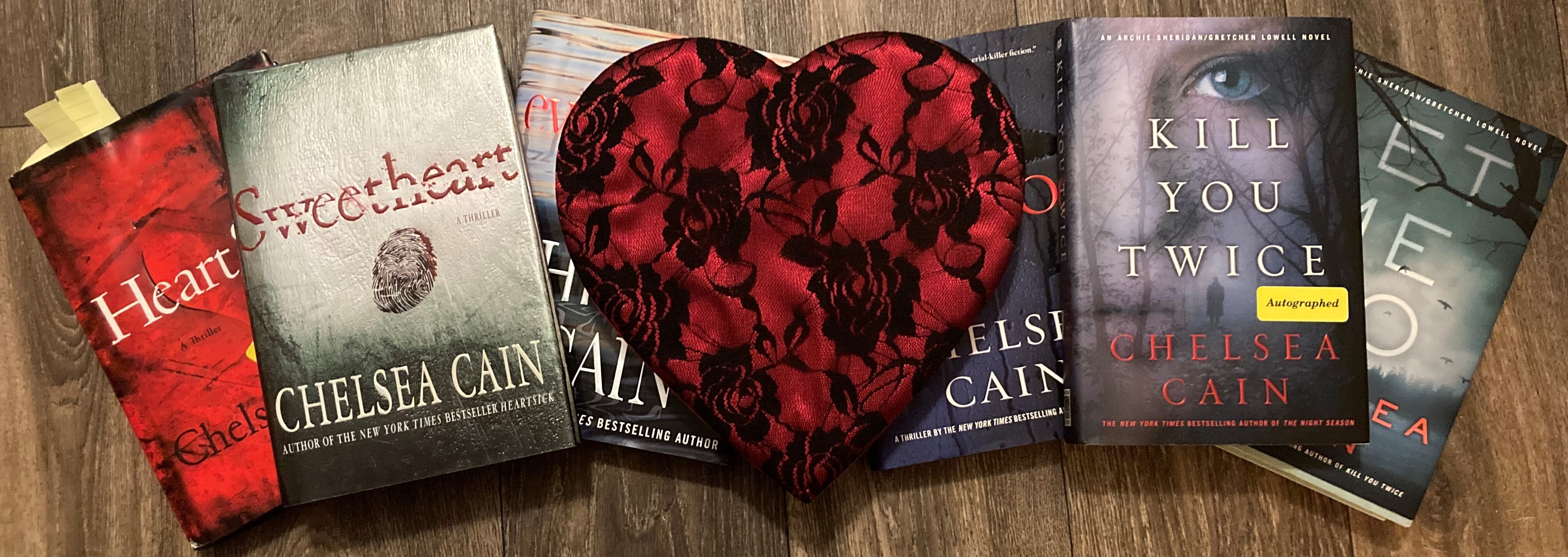 six hardcover Beauty Killer novels laid out in a row, with a heart-shaped box in the middle
